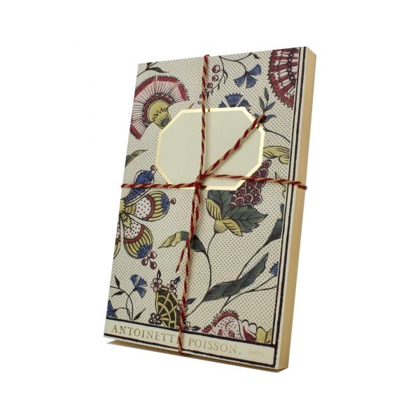 A notebook with a hand decorated domino paper cover that has a floral design