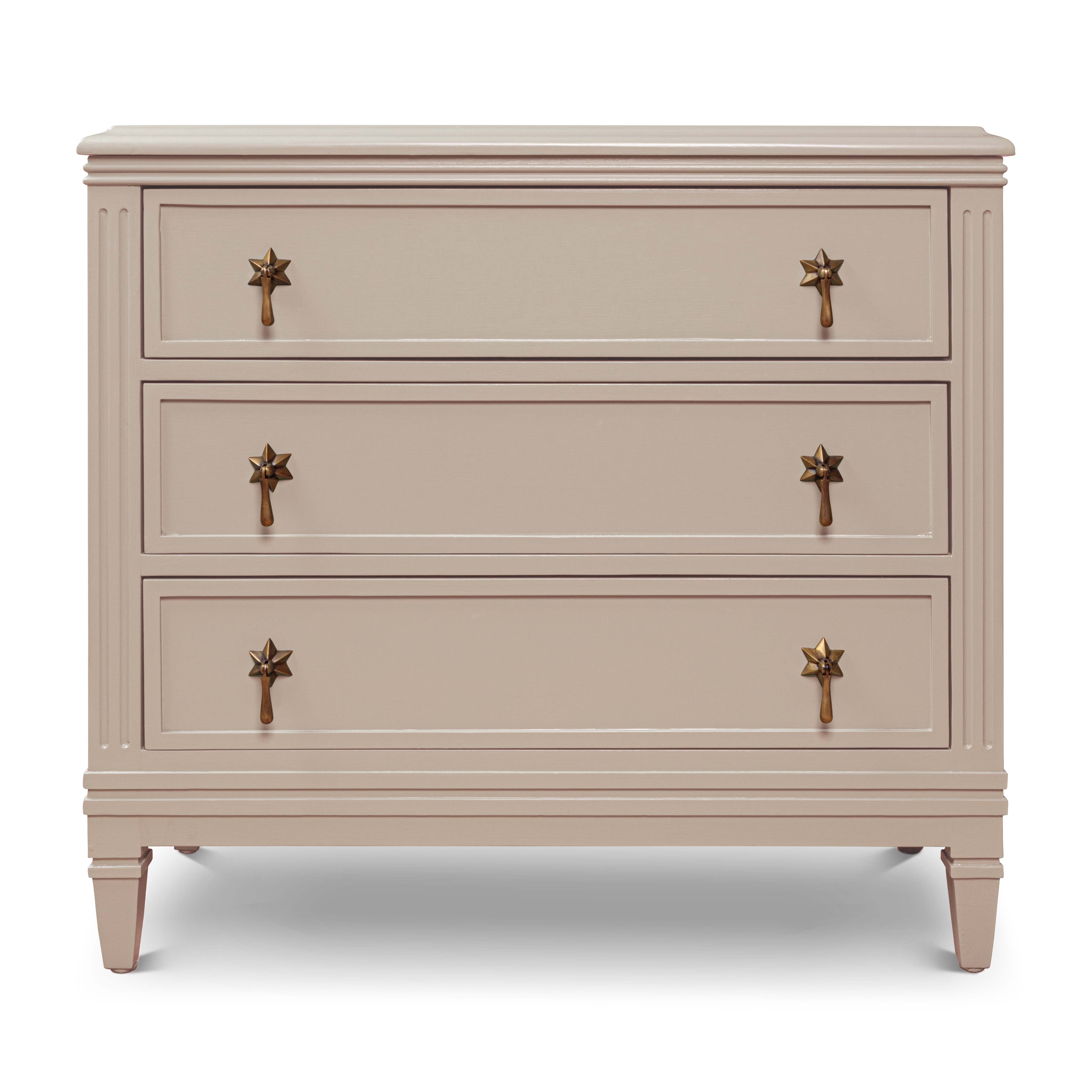A ecru-coloured chest of drawers with three compartments, each with two star-shaped handles.